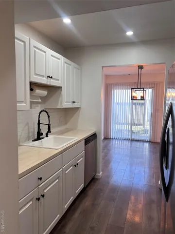 a view of a kitchen with kitchen island a sink wooden floor and a large window