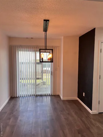 a view of empty room with floor to ceiling window and wooden floor