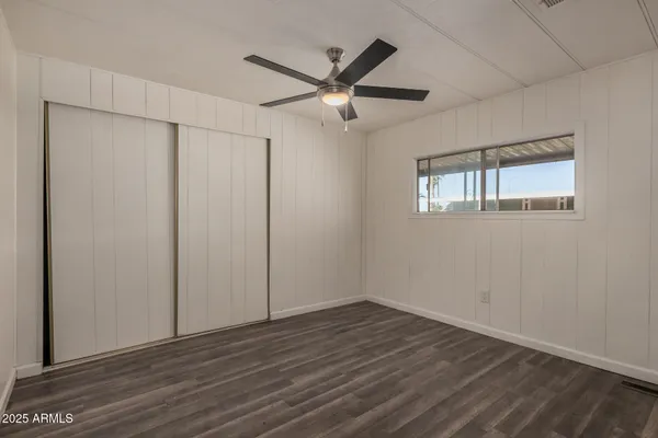 an empty room with wooden floor closet and windows