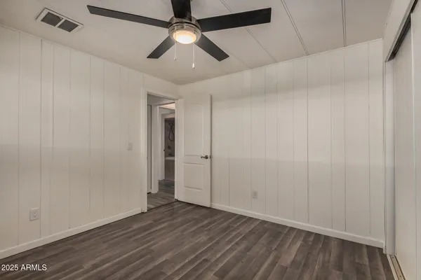 an empty room with wooden floor and ceiling fan