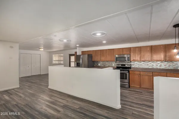 a large white kitchen with kitchen island a sink a stove a refrigerator cabinets and wooden floor