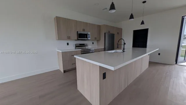 a kitchen with stainless steel appliances a white stove top oven a sink dishwasher and a refrigerator with wooden floor