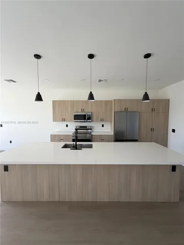 a large kitchen with stainless steel appliances a large counter top a stove and a refrigerator