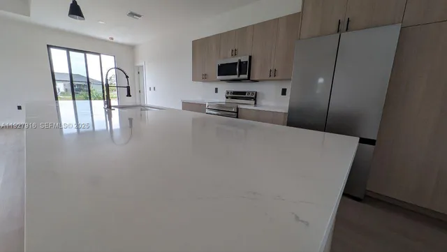 a kitchen with granite countertop a refrigerator a stove a sink and a large window