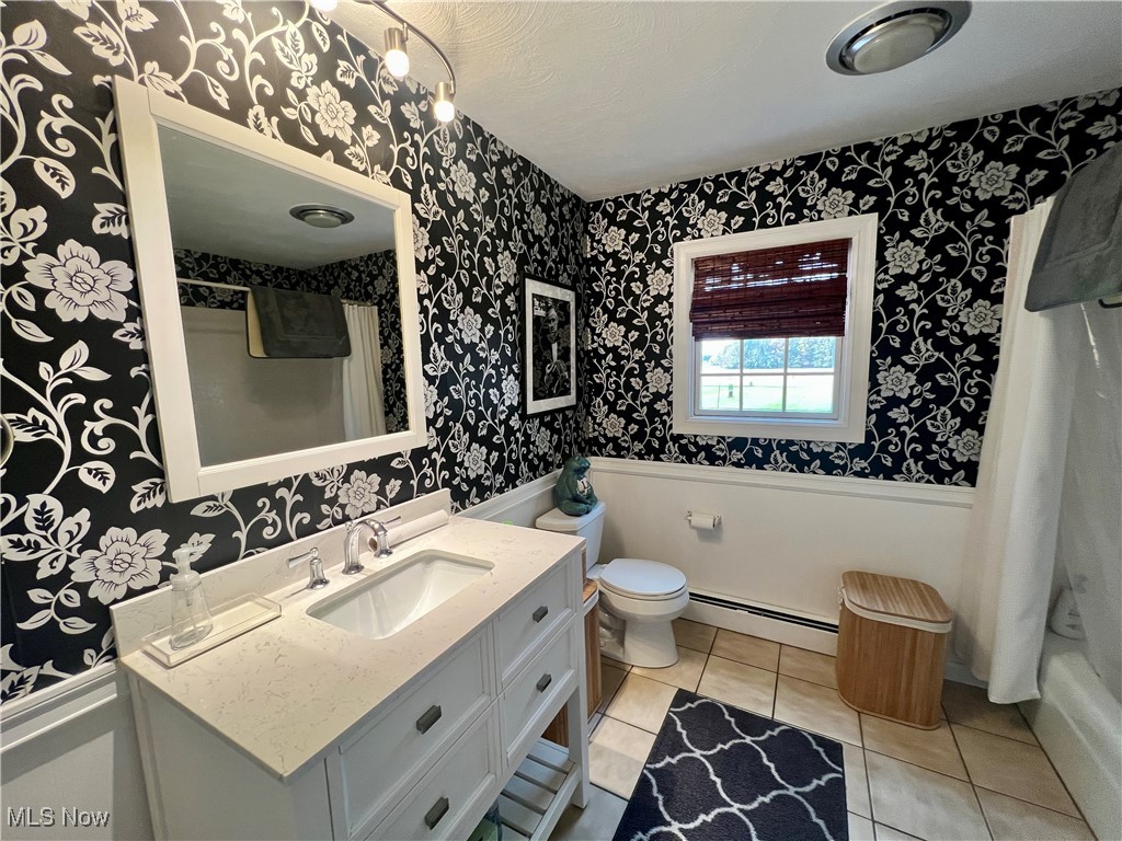446 Annis Road Amherst, OH 44001 - Photo 16 of 39 Full bathroom with shower / bathtub combination with curtain, toilet, vanity, baseboard heating, and tile patterned floors