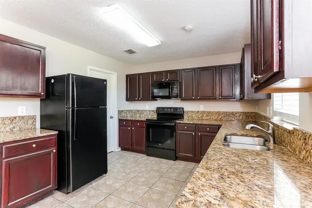 a kitchen with granite countertop wooden cabinets a refrigerator and a sink
