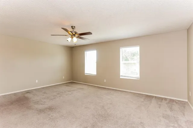an empty room with a window and a ceiling fan