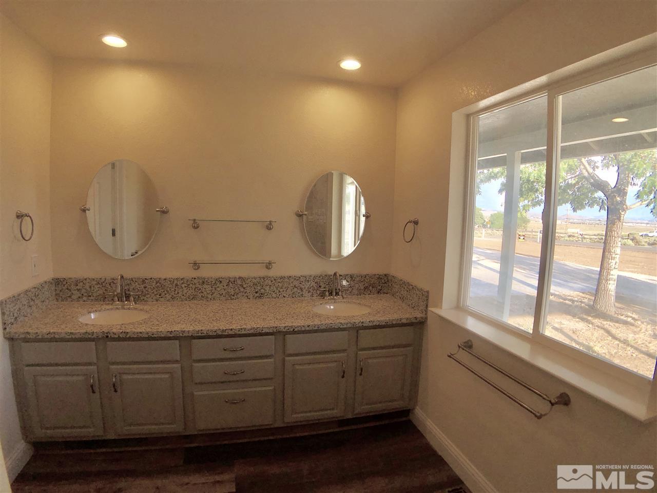 10205 Placerville Road Reno, NV 89508 - Photo 23 of 40 a bathroom with a granite countertop sink a large mirror and a window