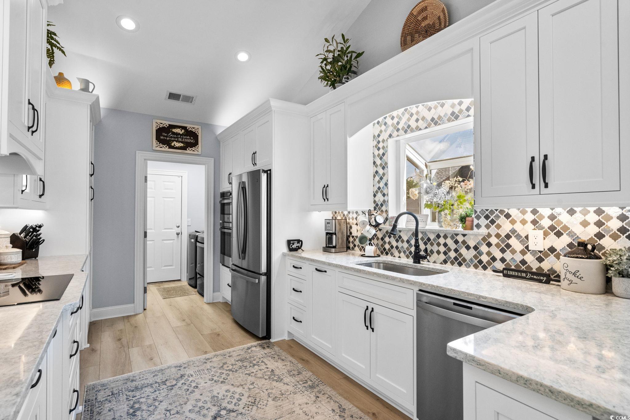 408 Highland Ridge Drive Myrtle Beach, SC 29588 - Photo 11 of 39 Kitchen featuring GE Profile appliances with stainless steel finishes, recessed lighting, light wood-type flooring, white cabinets, and tasteful backsplash