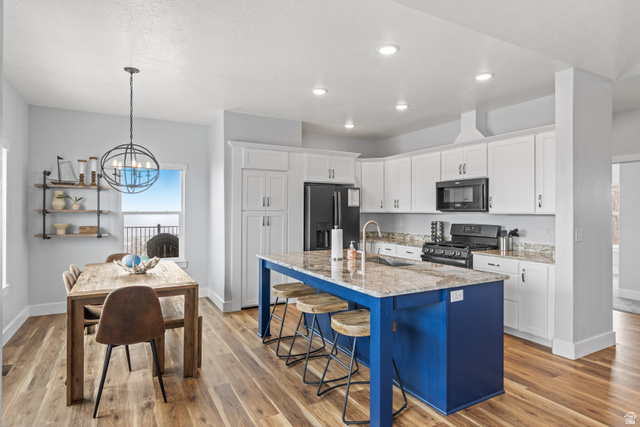 1343 North Trapper Loop Garden City, UT 84028 - Photo 26 of 56 Kitchen with a breakfast bar area, a center island with sink, gas range, refrigerator with ice dispenser, and light stone counters