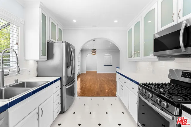 a kitchen with stainless steel appliances a refrigerator a sink a stove top oven a counter space and cabinets