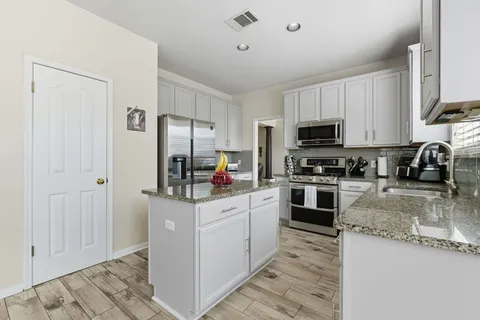 a kitchen with stainless steel appliances granite countertop a stove a sink and a microwave