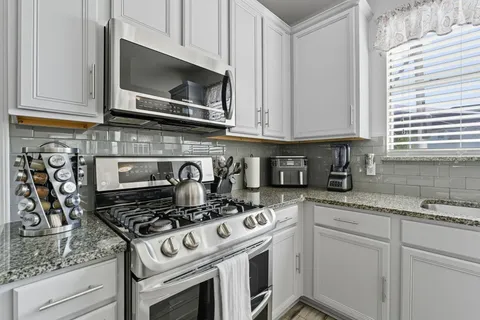 a kitchen with granite countertop a refrigerator stove and microwave