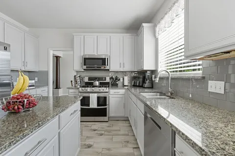 a kitchen with stainless steel appliances granite countertop a sink stove refrigerator and microwave