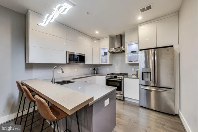 a kitchen with a refrigerator a stove a microwave and island with wooden floor