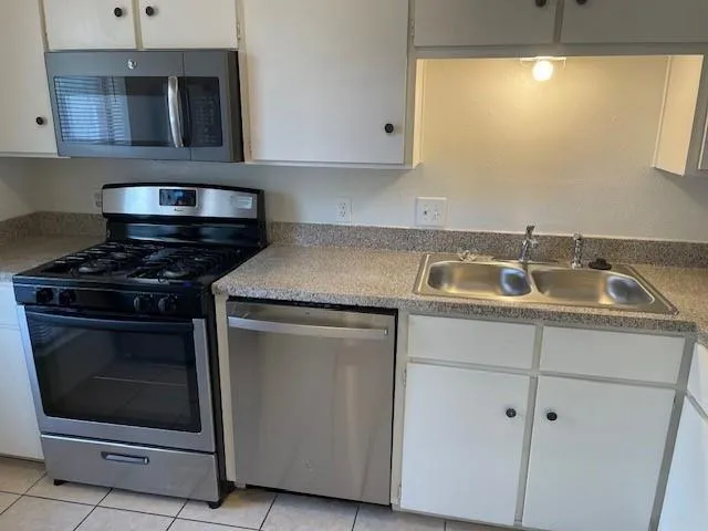 a kitchen with granite countertop white cabinets stainless steel appliances and sink