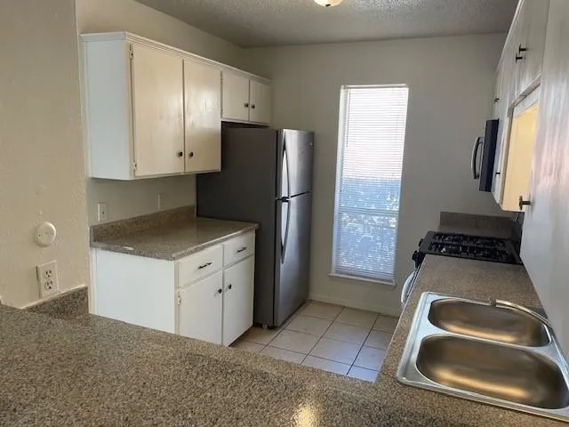 a kitchen with granite countertop a sink stove and refrigerator