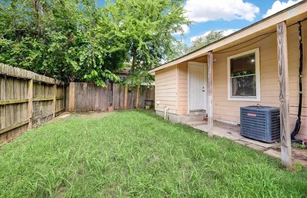 a backyard of a house with lawn chairs and a large tree