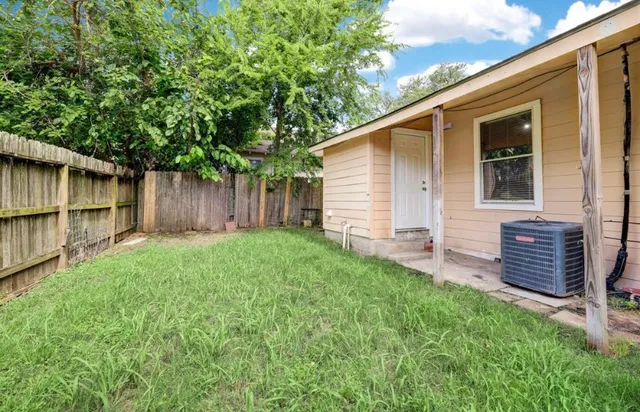 a backyard of a house with lawn chairs and a large tree
