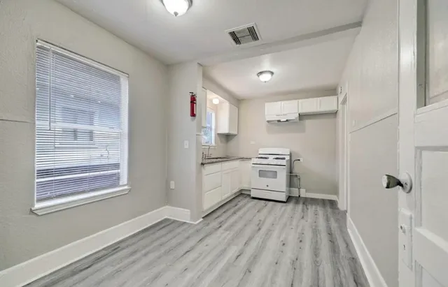 a kitchen with wooden floors appliances cabinets and a ceiling fan