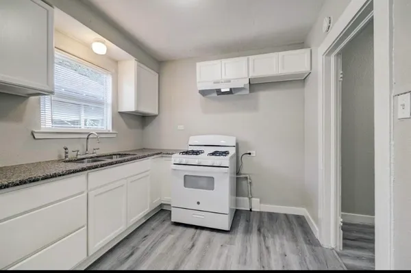 a kitchen with granite countertop wooden floors and white cabinets
