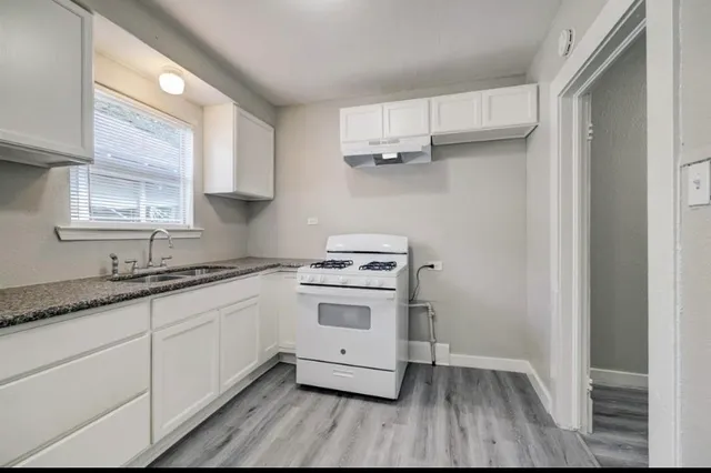 a kitchen with granite countertop wooden floors and white cabinets
