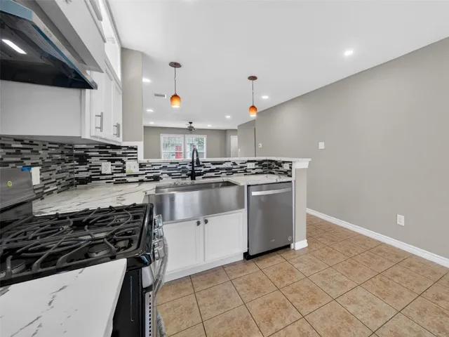 a kitchen with stainless steel appliances a white stove top oven a sink a counter space and cabinets