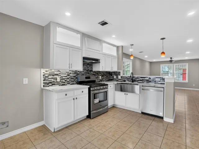 a kitchen with white cabinets a sink dishwasher and a stove with wooden floor