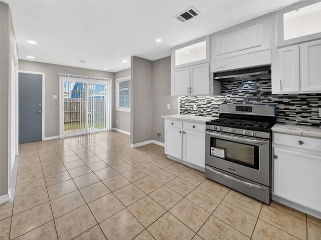 a kitchen with granite countertop a stove top oven cabinets and stainless steel appliances