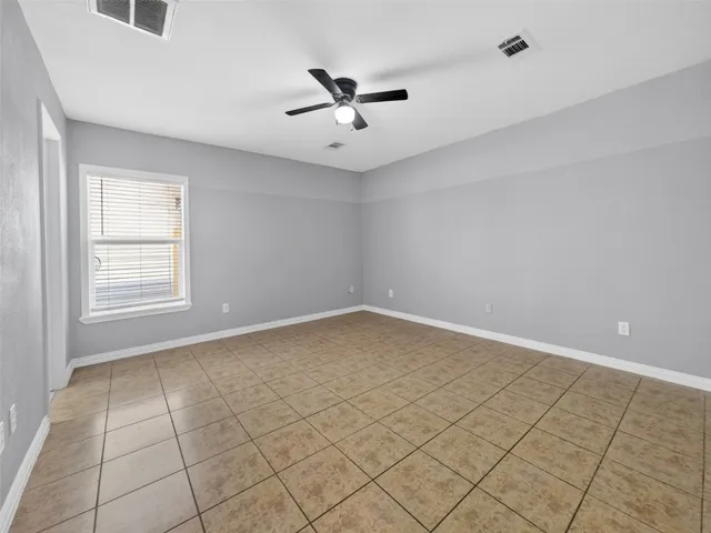 an empty room with windows and ceiling fan