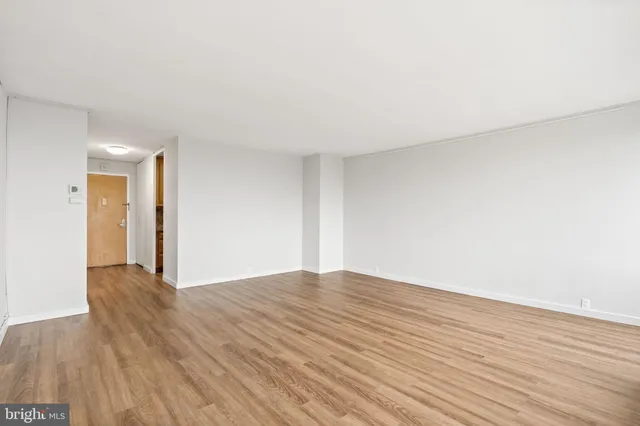 a view of an empty room with wooden floor and a window
