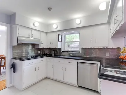 a kitchen with granite countertop white cabinets and white appliances