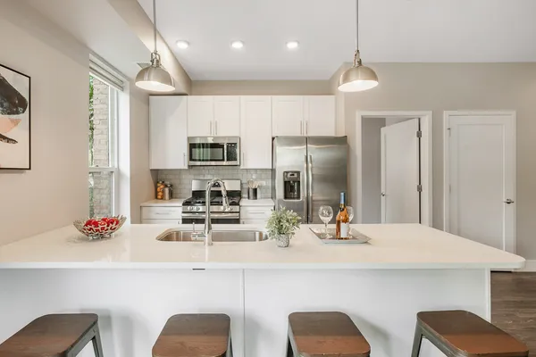 a kitchen with stainless steel appliances kitchen island granite countertop a dining table chairs refrigerator and sink