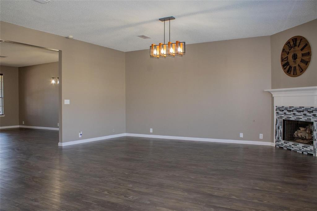 3240 Roddy Drive Fort Worth, TX 76123 - Photo 9 of 28 a view of an empty room with wooden floor and a fireplace