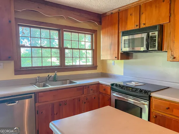 a kitchen with stainless steel appliances a sink a microwave a refrigerator and cabinets