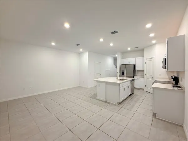 a large white kitchen with a white countertops a stove a sink and a refrigerator