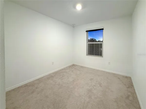 a view of an empty room with a kitchen and a window