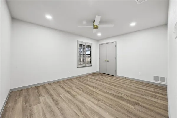 an empty room with windows and ceiling fan