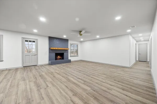 a view of an empty room with wooden floor and fireplace