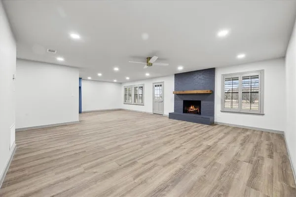 an empty room with wooden floor fireplace and windows