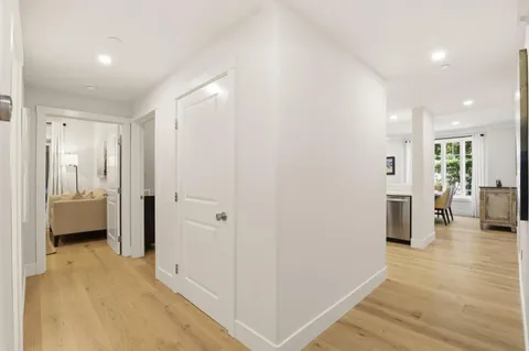 a view of a hallway with wooden floor and a living room