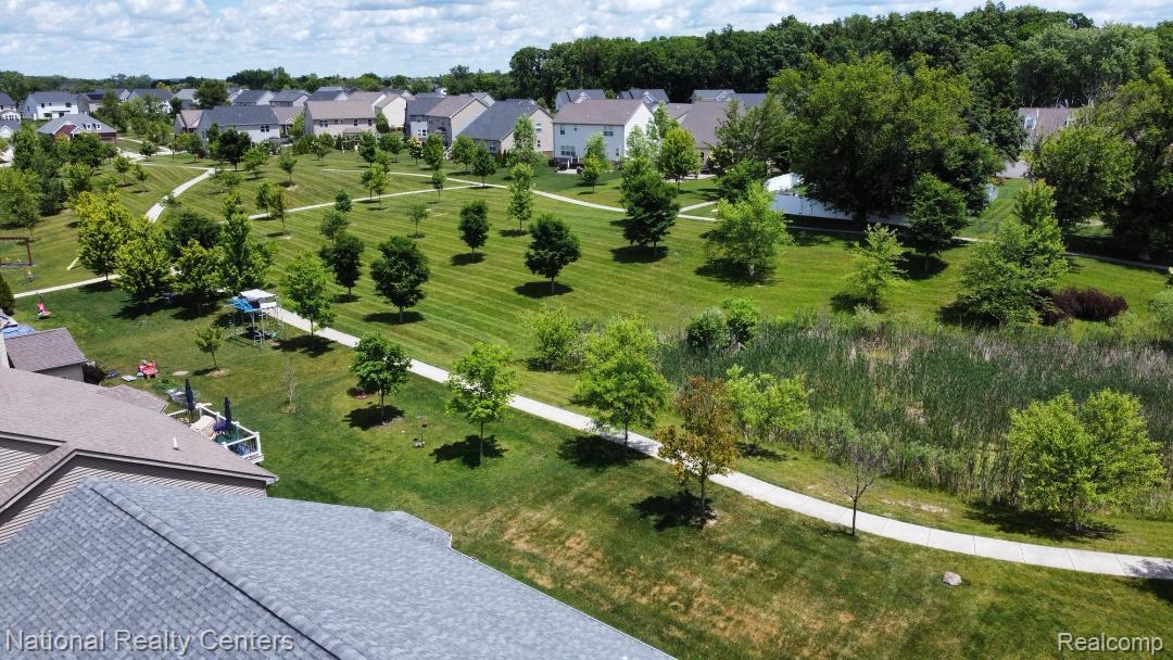 740 North Mill Street South Lyon, MI 48178 - Photo 4 of 56 Expansive green space featuring mature trees, manicured lawns, and winding paved pathways