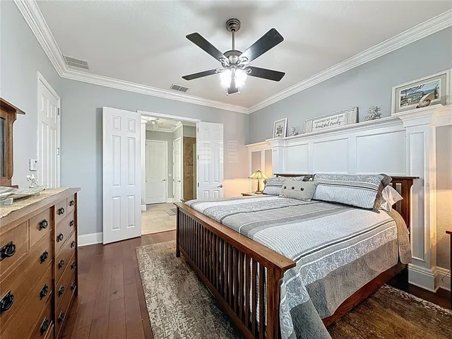 a bedroom with a bed and dresser with wooden floor