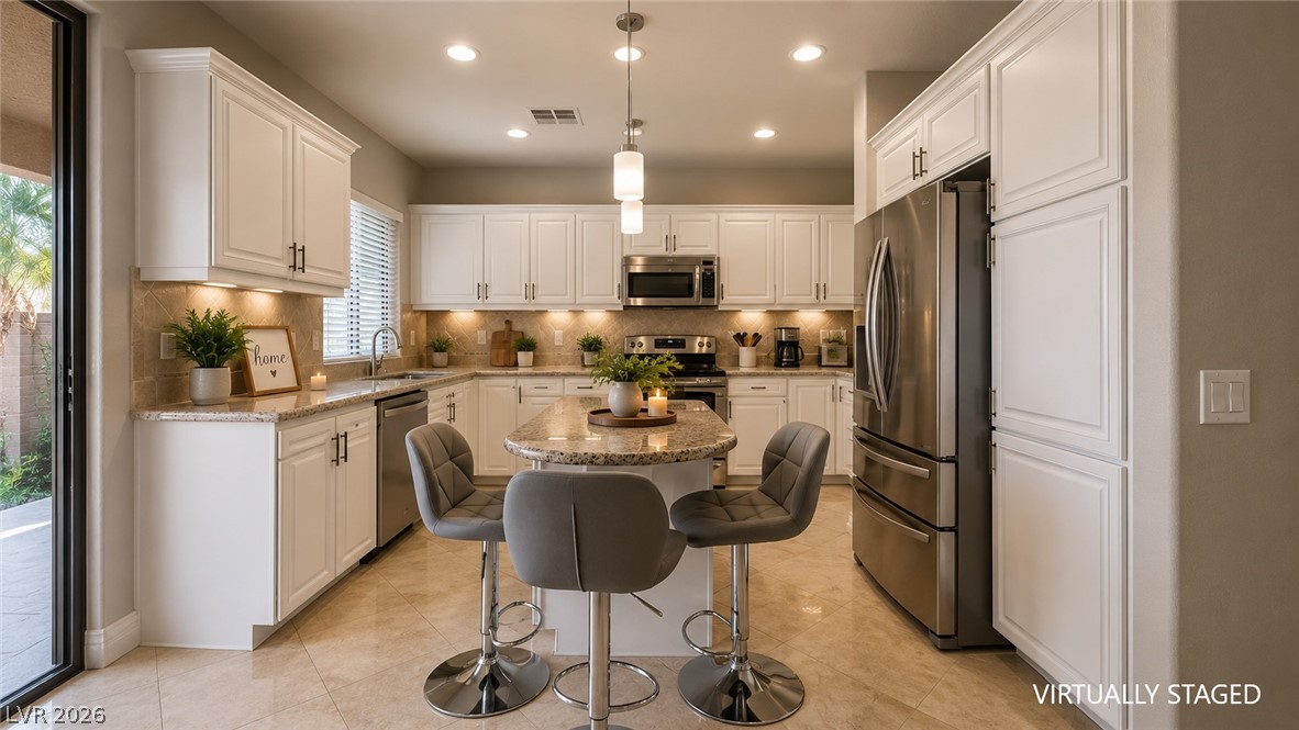 87 Tall Ruff Drive Las Vegas, NV 89148 - Photo 48 of 71 A chef's kitchen features an inviting center island with seating, creating a functional and stylish hub for culinary endeavors.