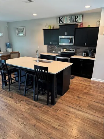 a kitchen with stainless steel appliances kitchen island granite countertop a table chairs a sink and a stove