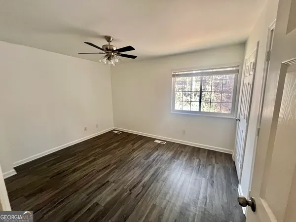 an empty room with wooden floor fan and windows
