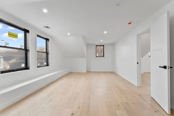 a view of an empty room with a window and kitchen view