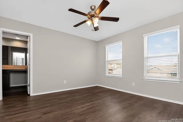a view of an empty room with window and wooden floor