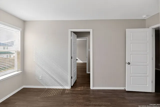 an empty room with wooden floor closet and windows