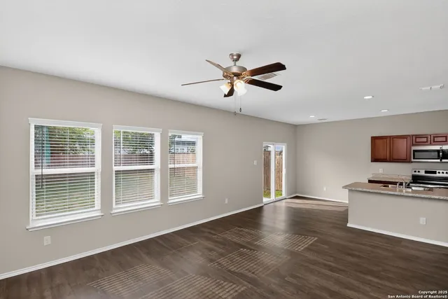 a view of a kitchen with furniture a ceiling fan and wooden floor